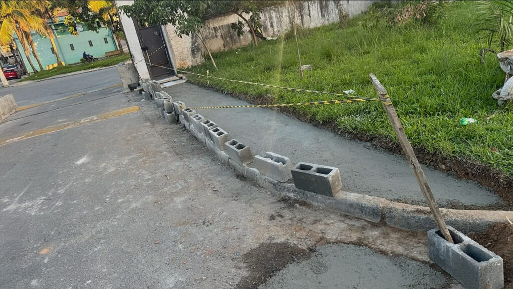 Calçada recém-concretada na entrada do residencial Victoria Park, com blocos e fita de isolamento ao redor, resultado do trabalho conjunto entre moradores e associação.
